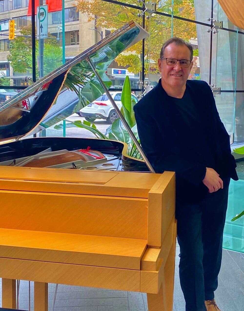 Robert Koziel standing beside a grand piano in downtown Vancouver
